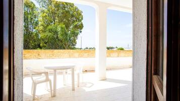 Eine Terrasse im Freien mit Tisch und Stühlen, eine Steinmauer und ein Baum im Hintergrund.