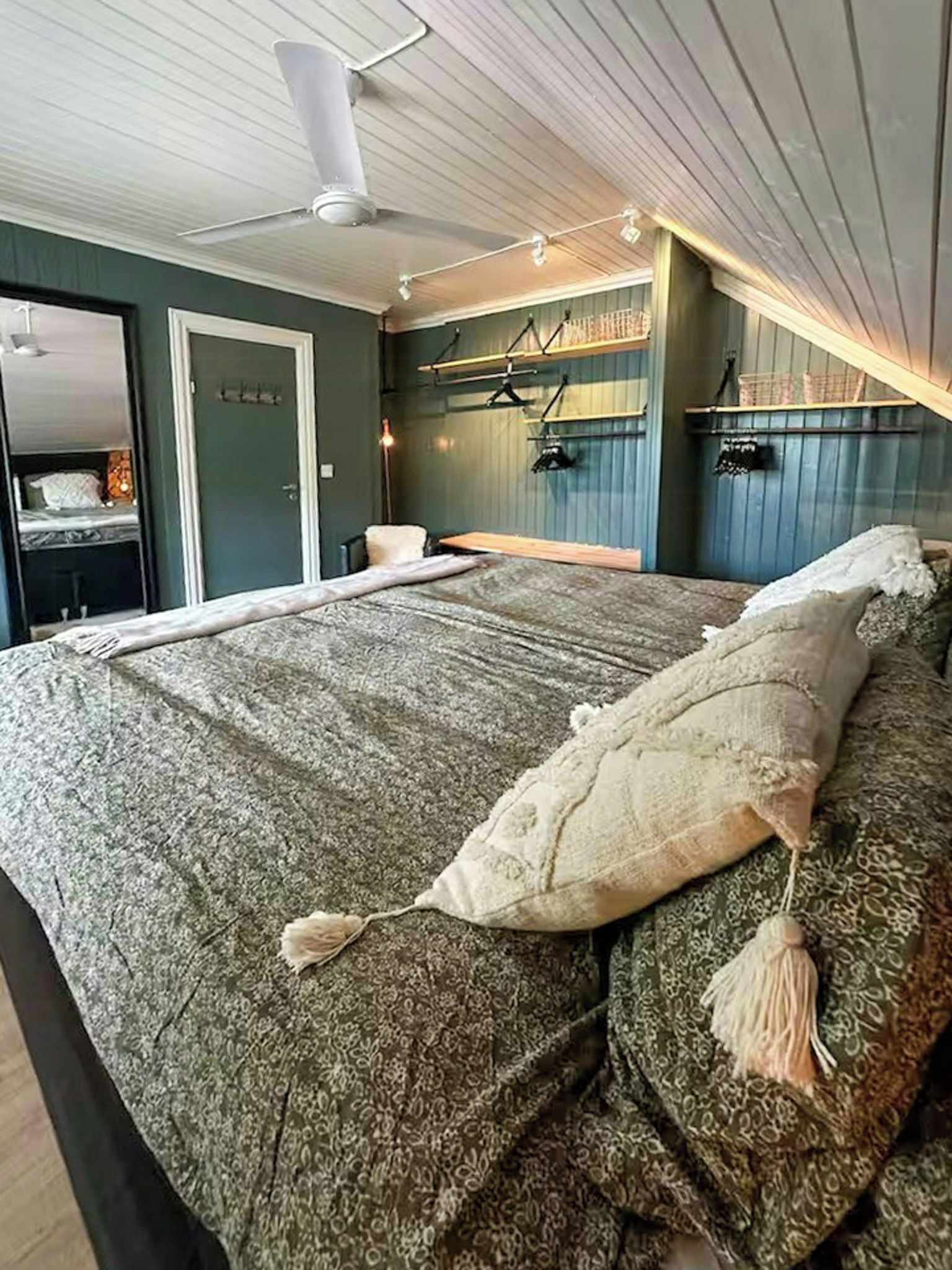 Un dormitorio con una cama grande, un ventilador de techo y un armario.