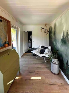 Un pasillo con una cama, un mapa en la pared y un cuadro grande con árboles.