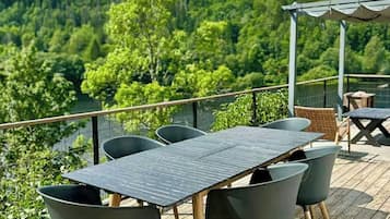 Une terrasse extérieure avec une table et des chaises, offrant une vue sur un paysage boisé.