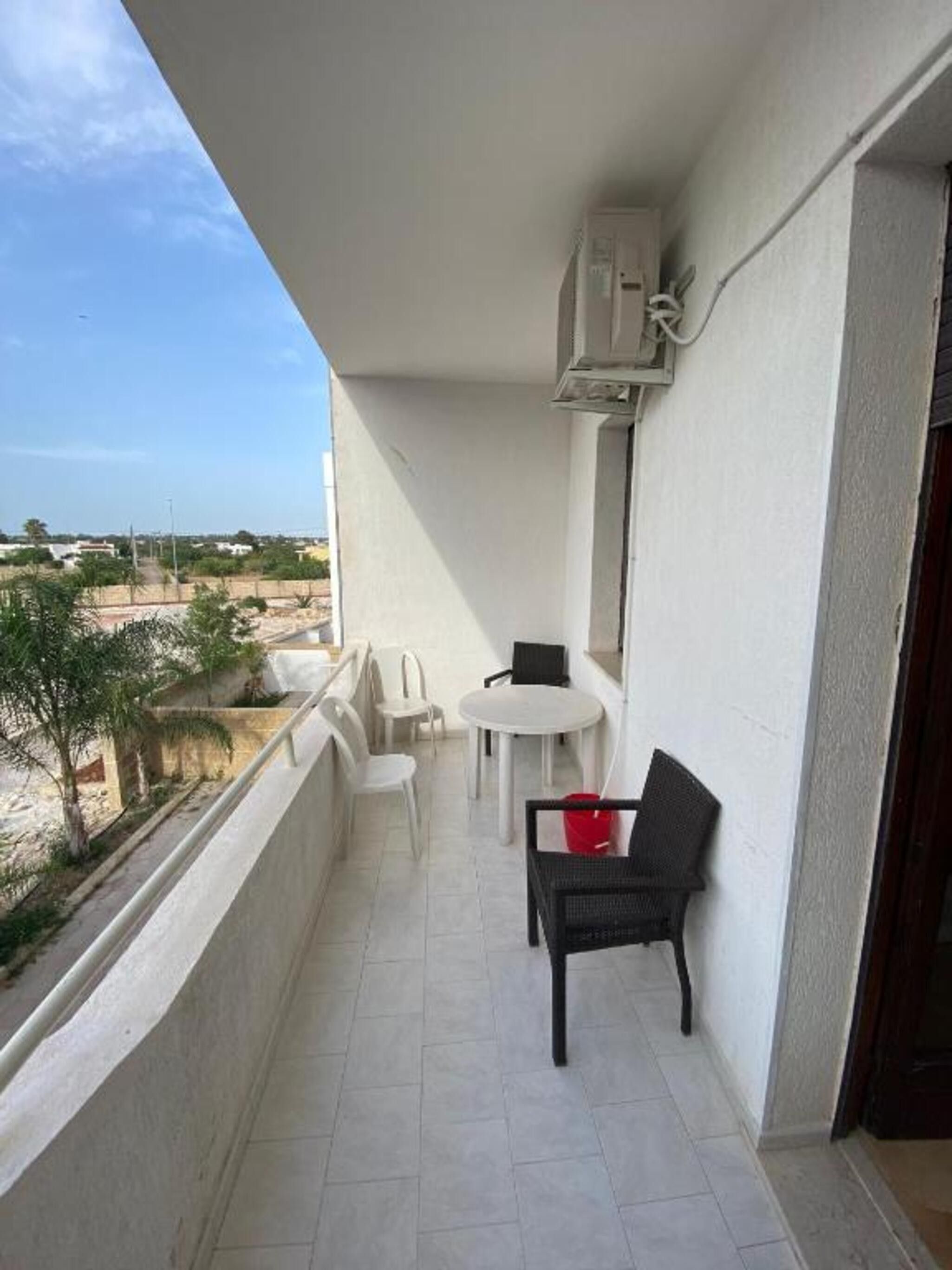 Ein Balkon mit einem weißen Tisch, zwei Stühlen und einem schwarzen Sessel.