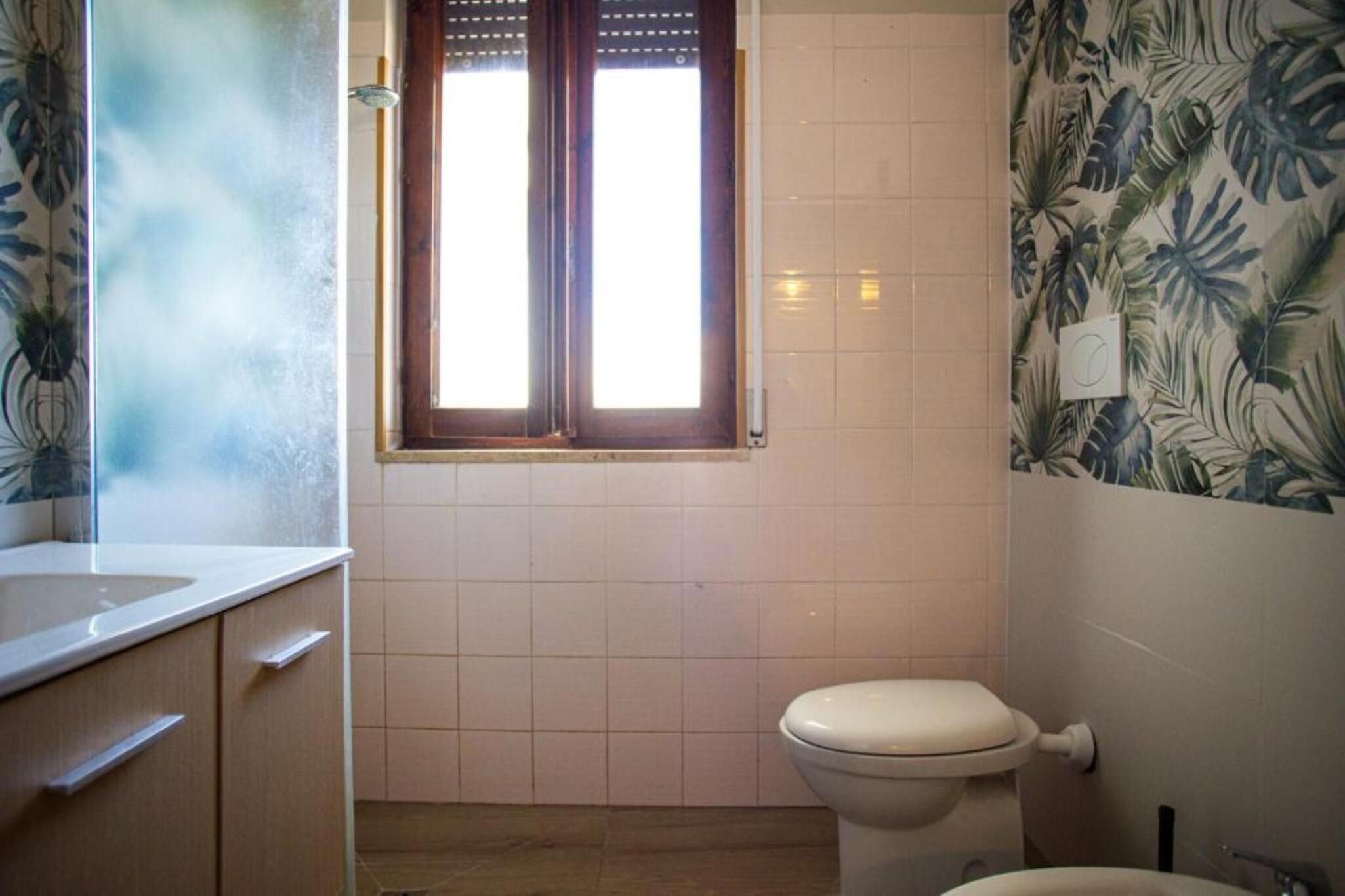 Un baño con inodoro, ventana y lavabo.