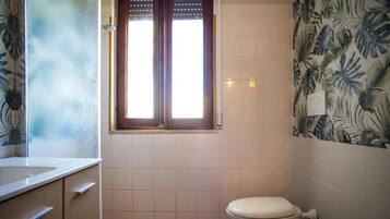 Un baño con inodoro, ventana y lavabo.
