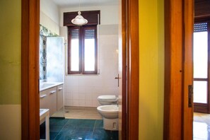 A bathroom with a toilet, bidet, and a window with blinds. - Apartment 'Residence Eriguez - 2' with Shared Pool, Wi-Fi and Air Conditioning (Marina di Mancaversa)
