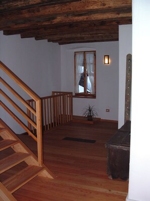 A wooden staircase leading to a landing with a window and a potted plant. - A historic house in a small mountain village near the Adamello-Brenta Nature Park. (Ragoli - Tre Ville)