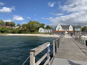 A wooden pier extending into calm waters, with a row of buildings and trees in the background. - Villa Mare Sea View (Gluecksburg)