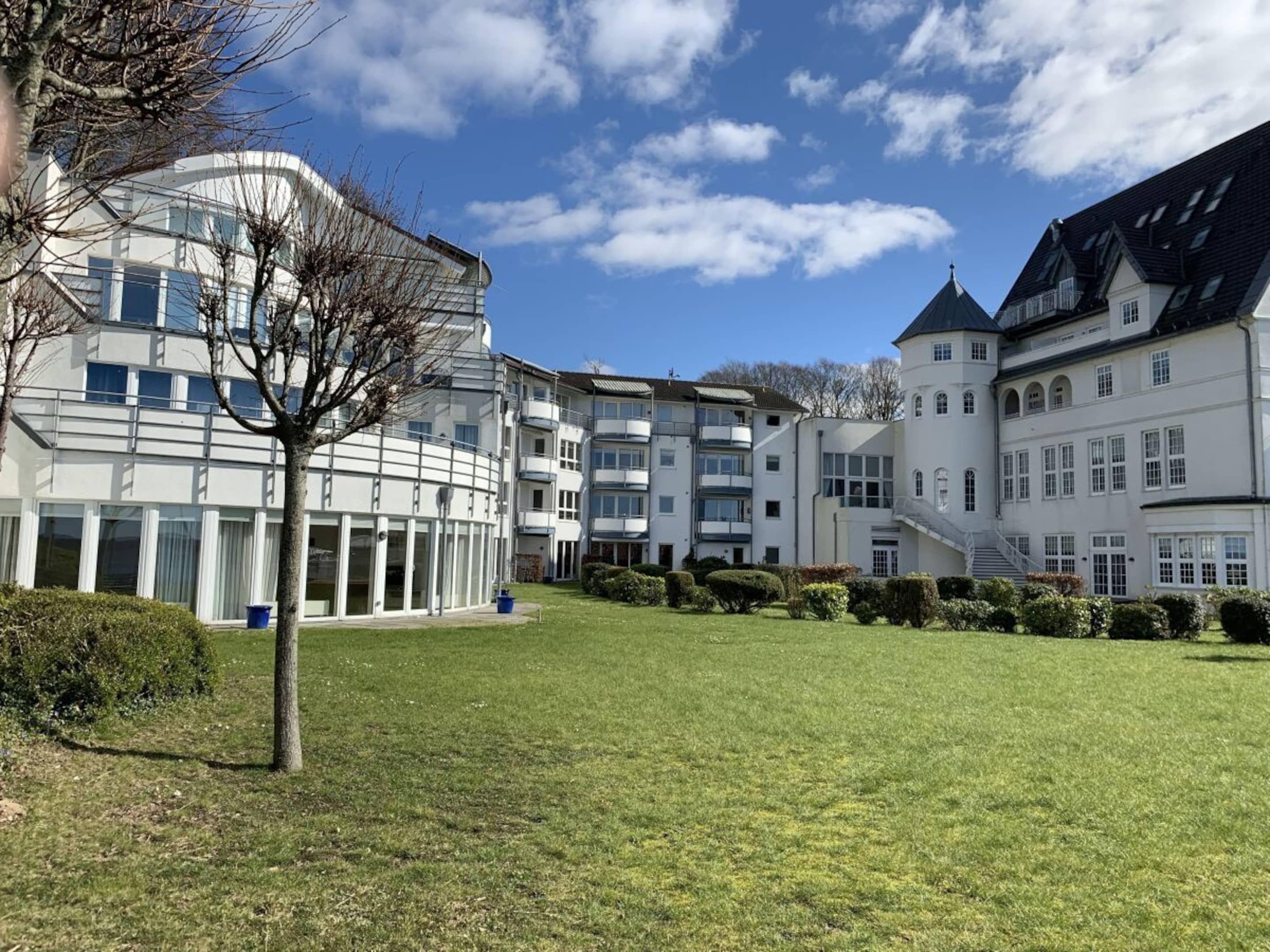 Un bâtiment moderne à étages, doté d’une cour intérieure, et un bâtiment traditionnel avec un toit en pente.
