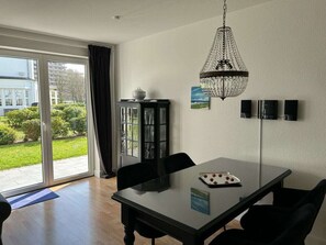 A modern dining area with a glass table, black chairs, a chandelier, and a cabinet with glass doors. - Villa Mare Sea View (Gluecksburg)