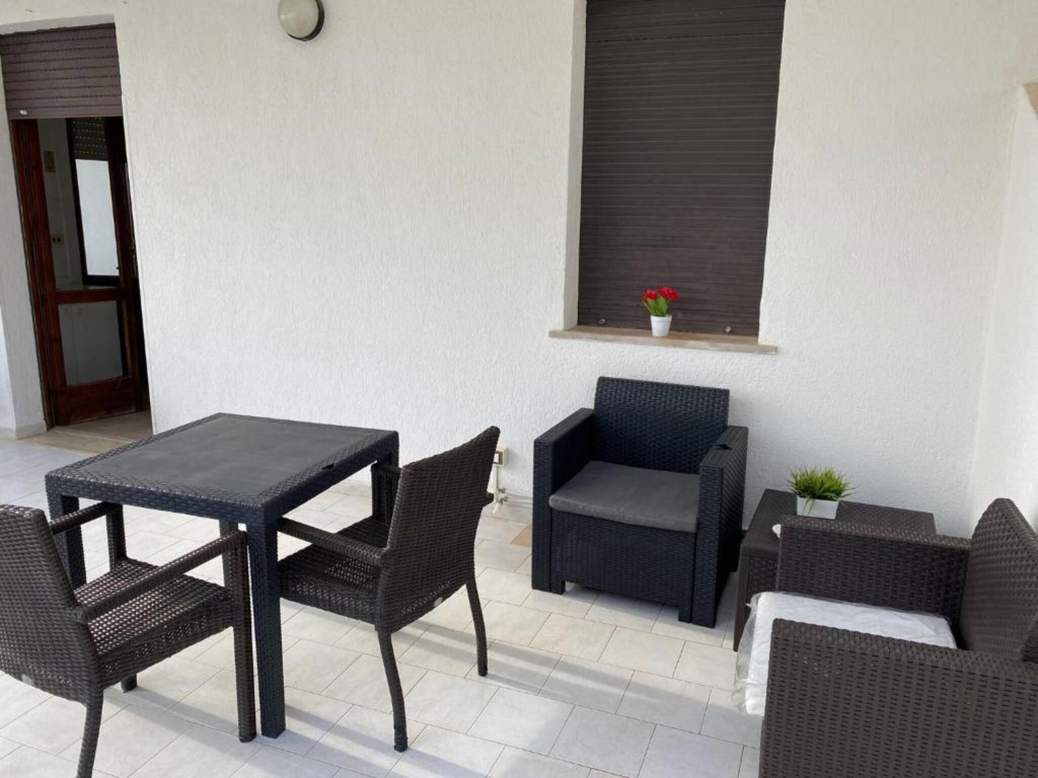 Un patio con una mesa y sillas, un sofá y una ventana con una planta.