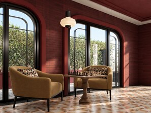 A room with two armchairs, a chess table, and large windows with a view of greenery. - Axis.Bangkok Chess (Bangkok)
