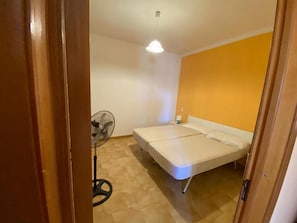A room with a bed, a standing fan, and a ceiling light. - Apartment 'Residence Eriguez - 5' with Shared Pool, Wi-Fi and Air Conditioning (Marina di Mancaversa)