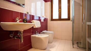 Ein Badezimmer mit Waschbecken, Toilette, Bidet und einer Duschkabine aus Glas.