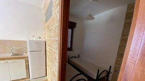 Cozinha compacta com geladeira, pia e bancada.