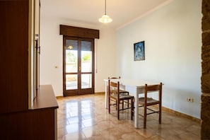 Una stanza con un tavolo e sedie in legno, una lampada a sospensione e una porta con finestra.