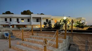 A set of outdoor stone steps leading to a building with a flat roof, a pool, and a chair. - Apartment 'Residence Eriguez - 8' with Shared Pool, Wi-Fi and Air Conditioning (Marina di Mancaversa)