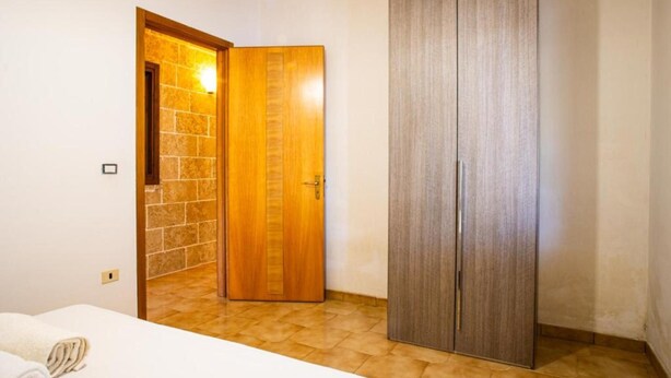 A room with a bed, a wooden wardrobe, and a door leading to another room. - Apartment 'Residence Eriguez - 8' with Shared Pool, Wi-Fi and Air Conditioning (Marina di Mancaversa)