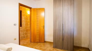 A room with a bed, a wooden wardrobe, and a door leading to another room.
