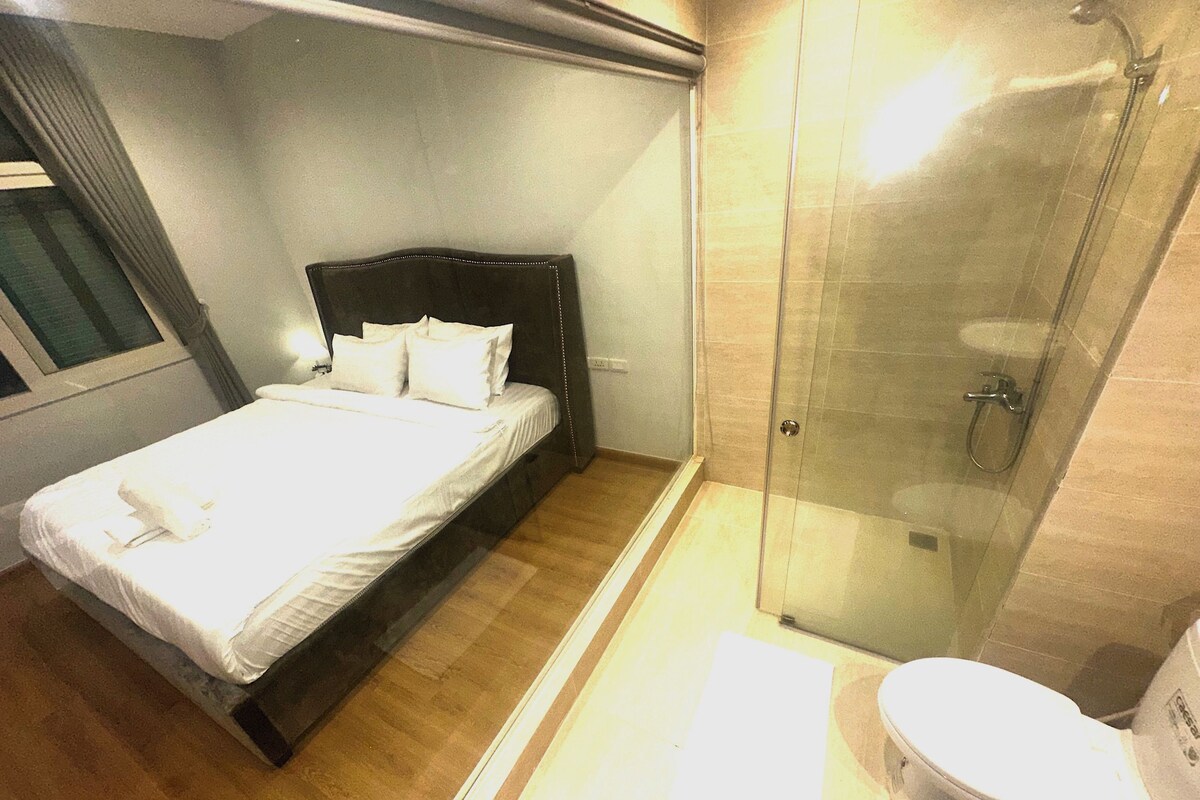 A hotel room with a bed, a shower, and a toilet.