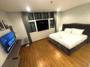 Una habitación de hotel con cama, televisión, escritorio y ventana.