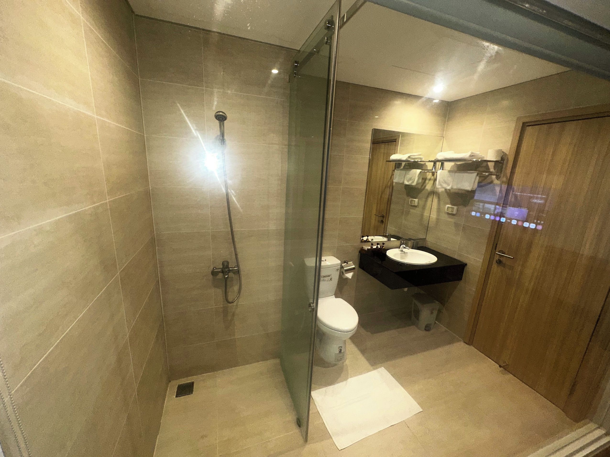 Une salle de bain moderne avec une douche à parois de verre, des toilettes et un lavabo surmonté d’un miroir.