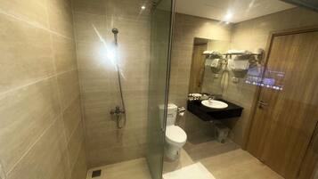 Une salle de bain moderne avec une douche à parois de verre, des toilettes et un lavabo surmonté d’un miroir.