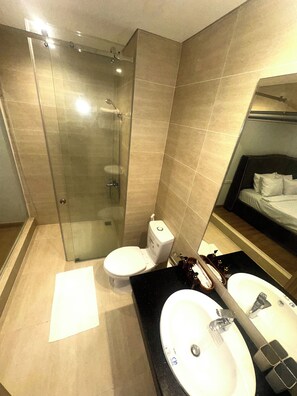 A modern bathroom with a glass-enclosed shower, a toilet, and a double sink with a mirror above. - Daimond Suite Lotus Village (Phu Quoc)