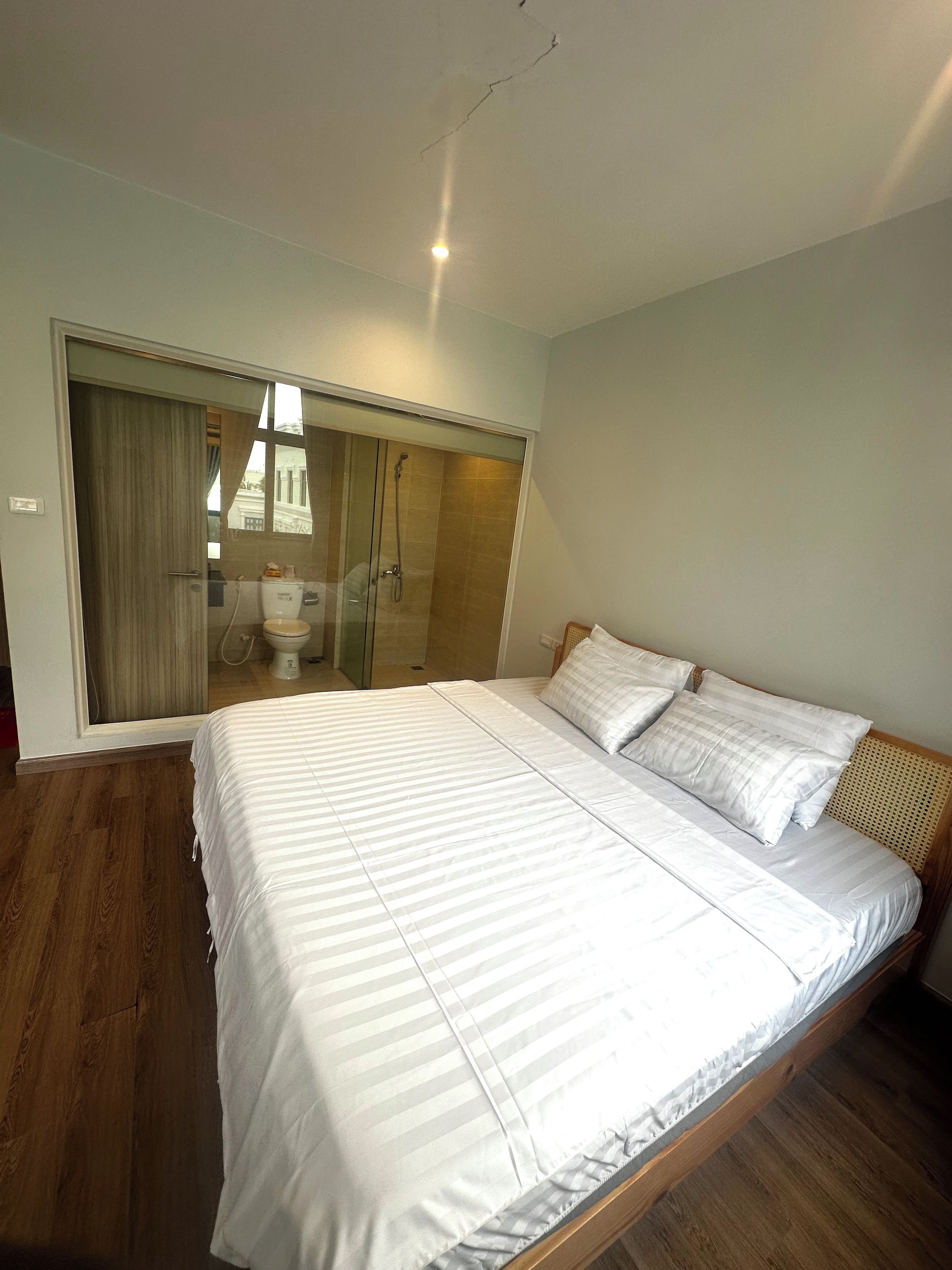 Une chambre avec un grand lit, un plancher en bois, une cabine de douche en verre et une armoire.