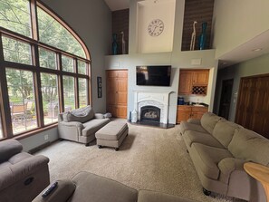Un salón espacioso con chimenea, ventanas amplias y un televisor de pantalla plana.