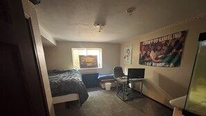 A bedroom with a bed, a desk with a laptop, a window, and posters on the wall. - EAA Exquisite 6-bedroom 3.5 bathroom house w AC on water only 8 minutes from EAA (Oshkosh)