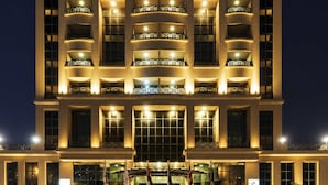 A multi-story building with balconies, a central entrance, and flags. - Opera Grand Hotel Deira (Dubai)