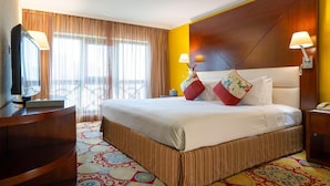 A hotel room with a large bed, a television, a desk, and a window with curtains. - Opera Grand Hotel Deira (Dubai)