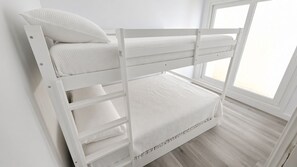 Een stapelbed met wit beddengoed en een raam met uitzicht.