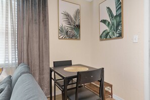 Ein Essbereich mit Tisch und Stühlen, einer Couch und zwei gerahmten Pflanzenbildern an der Wand.