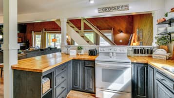 A kitchen with dark wooden cabinets, a white stove, and a wooden countertop.