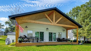 A covered outdoor patio with a dining area, a grill, and an American flag.