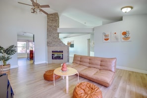 A modern living room with a stone accent wall, a leather sofa, a round coffee table, and a fireplace. - Home w/ Putting Green, 11 Mi to Las Vegas Strip! (North Las Vegas)