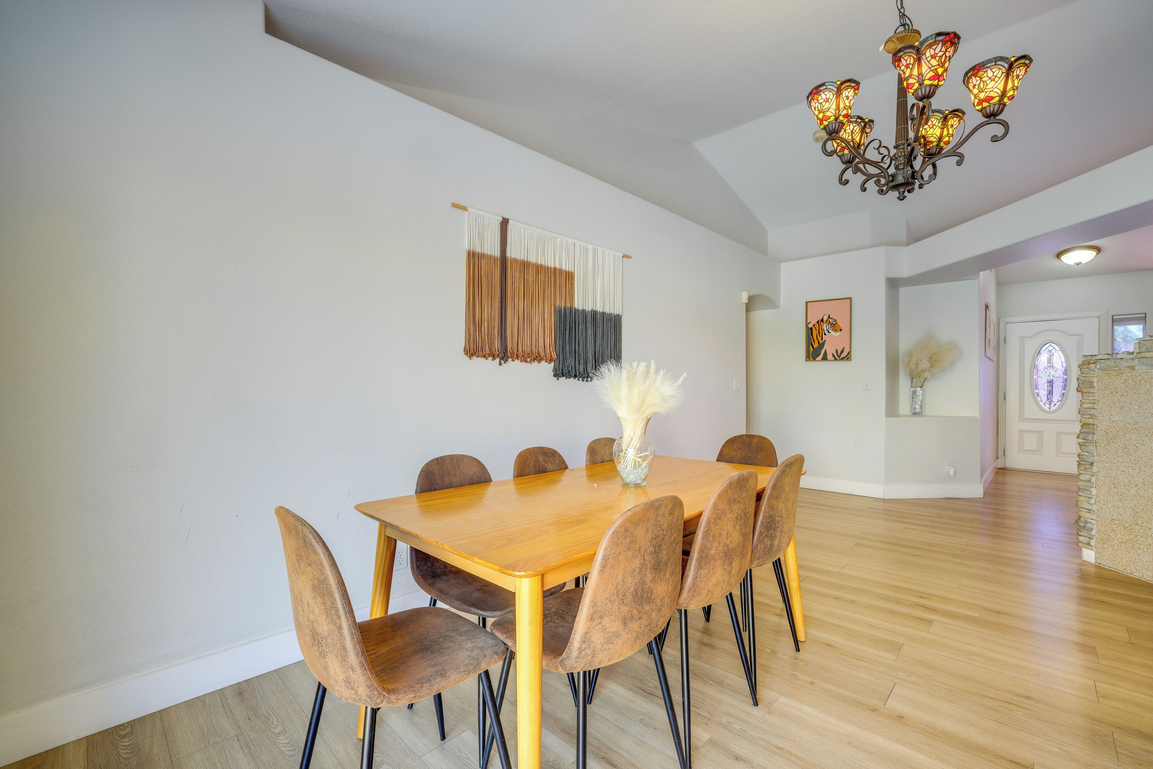 A dining area with a wooden table and chairs, a chandelier, and a wall-mounted tapestry.