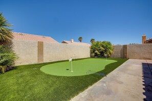 A well-maintained backyard with a putting green, palm trees, and a stone wall. - Home w/ Putting Green, 11 Mi to Las Vegas Strip! (North Las Vegas)