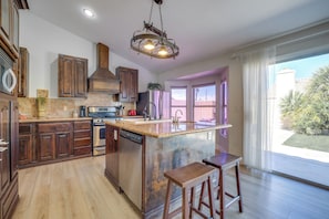 A kitchen with wooden cabinets, a stainless steel refrigerator, a built-in oven, and a large island with stools.