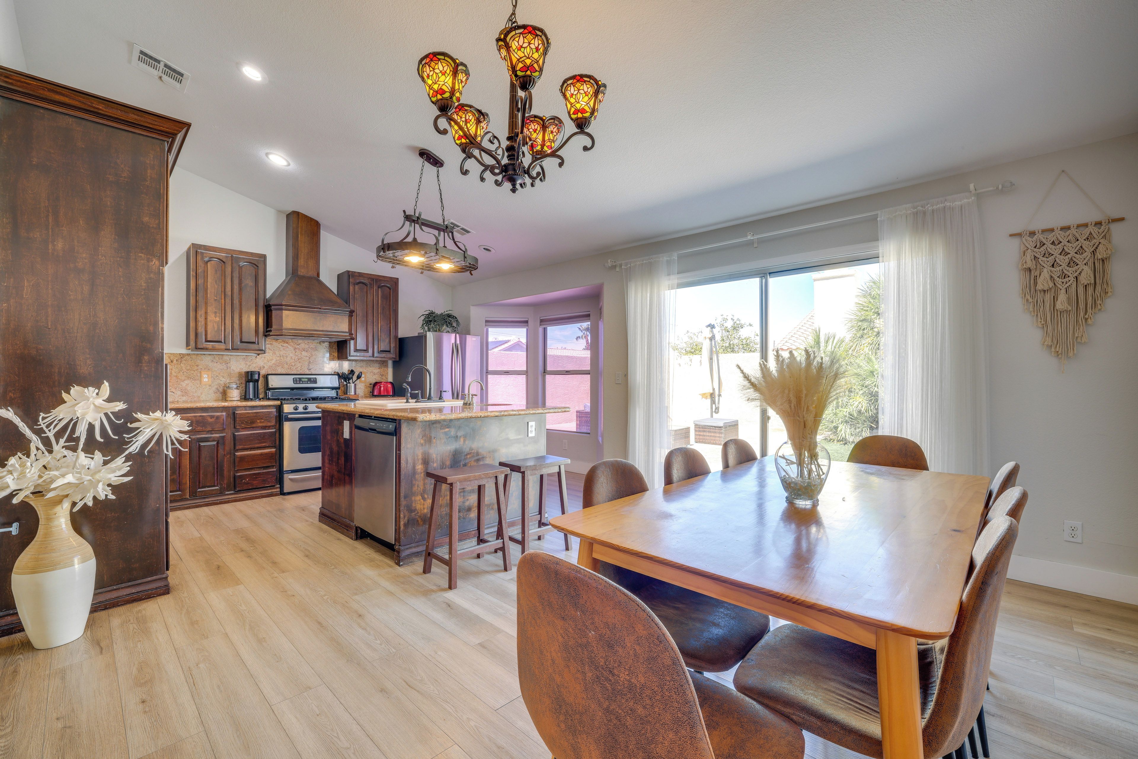 A modern kitchen with a central island, wooden cabinets, and a dining area with a large table and chairs.