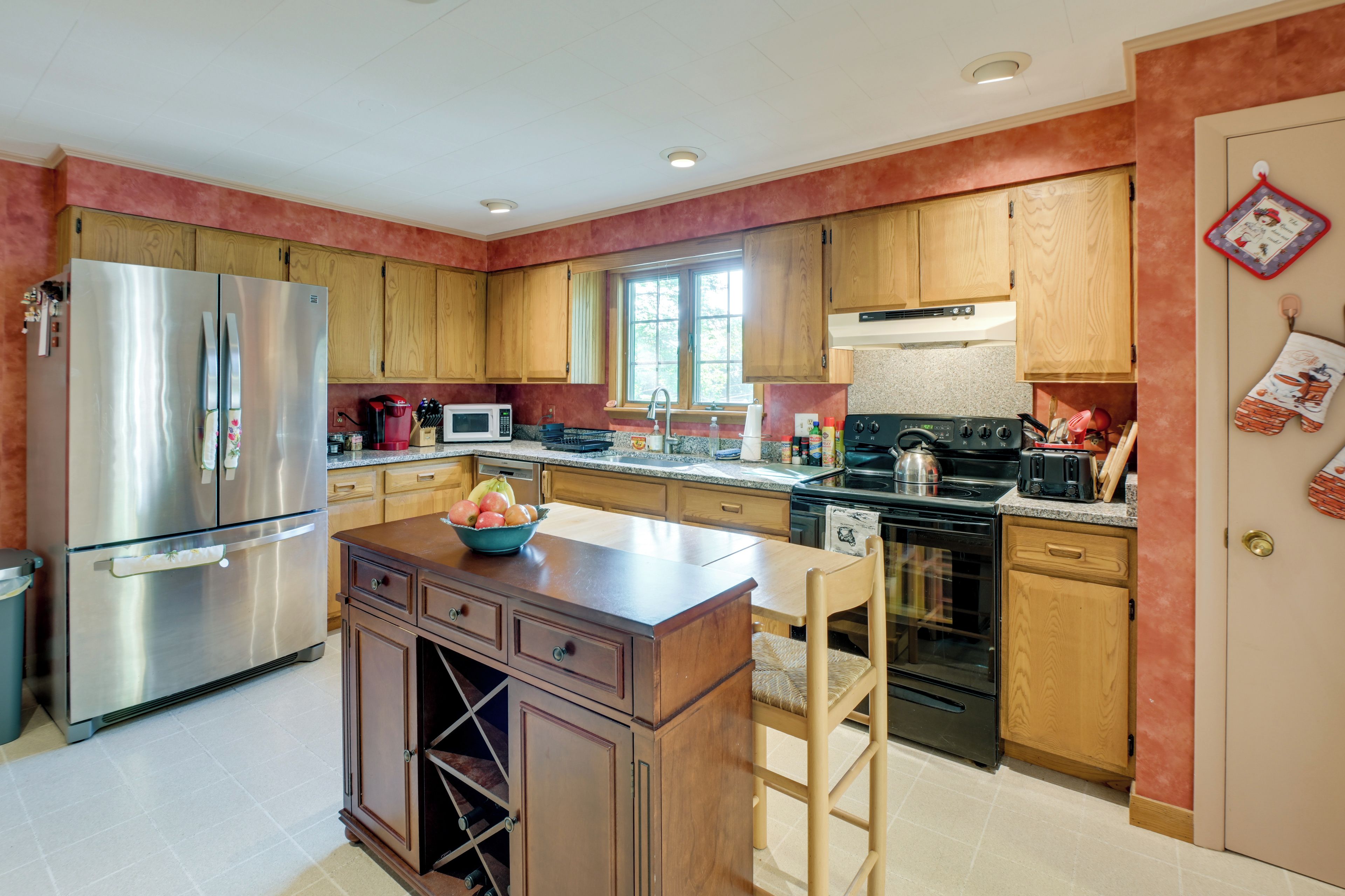 A modern kitchen with stainless steel appliances, wooden cabinets, and a central island.