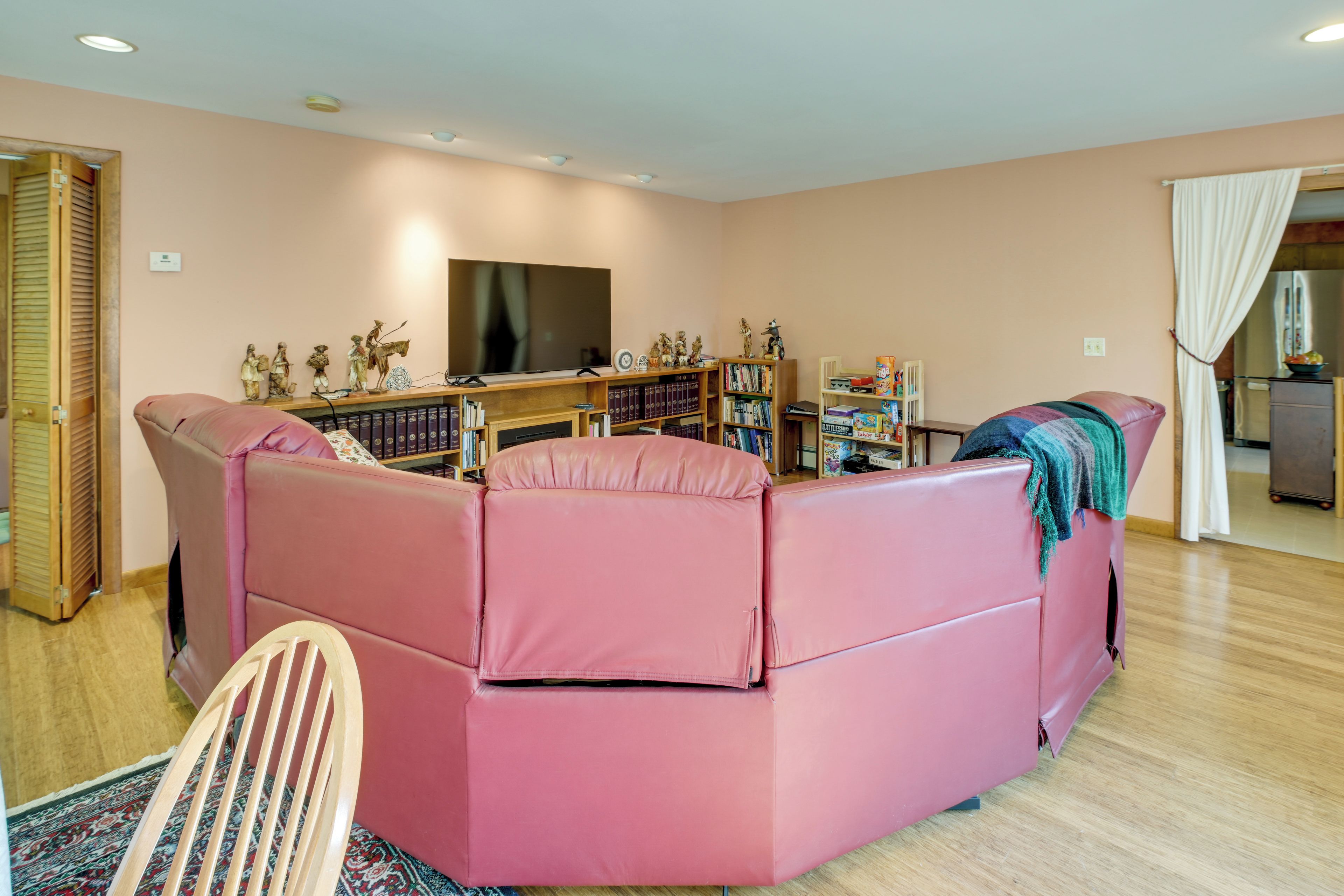 A living room with a pink sofa, a television, and a bookshelf.