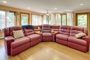 A room with a sectional sofa, a ceiling fan, and large windows. - Gateway to Acadia Nat'l Park! Peaceful Home (Ellsworth)