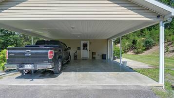 A covered garage with a black pickup truck parked inside.