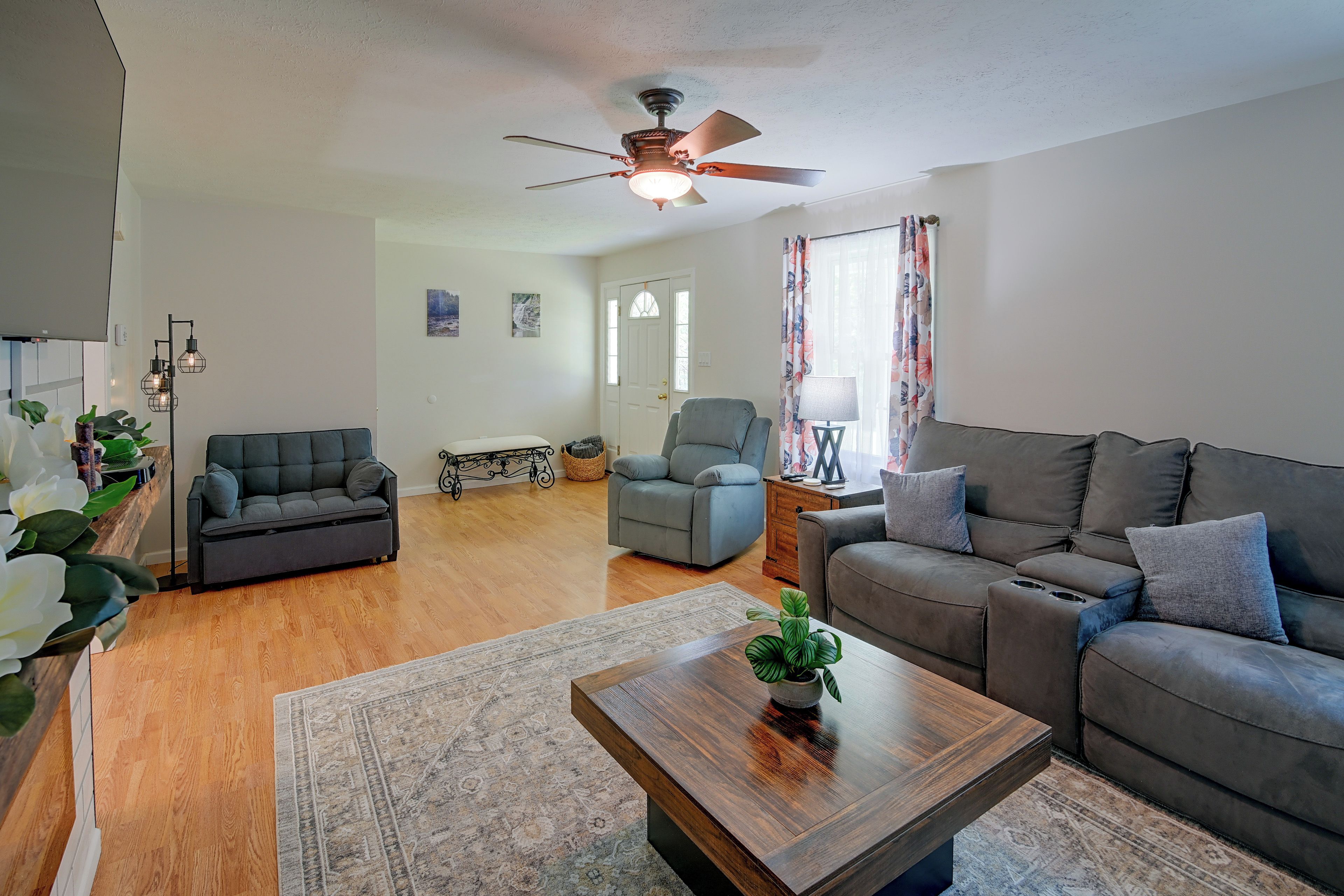 A spacious living room with a ceiling fan, two sofas, a coffee table, and a rug.