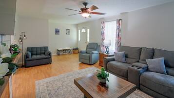A spacious living room with a ceiling fan, two sofas, a coffee table, and a rug.