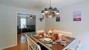 A dining area with a wooden table set for a meal, a chandelier, and a painting on the wall. - Private Yard: Fire Pit & Cornhole! Moorefield Gem (Moorefield)