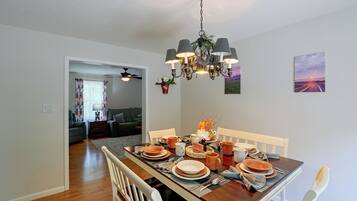 A dining area with a wooden table set for a meal, a chandelier, and a painting on the wall.