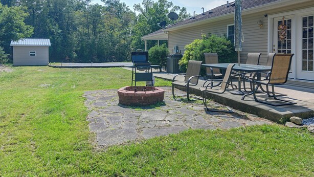 A backyard with a fire pit, outdoor furniture, and a house with a satellite dish. - Private Yard: Fire Pit & Cornhole! Moorefield Gem (Moorefield)
