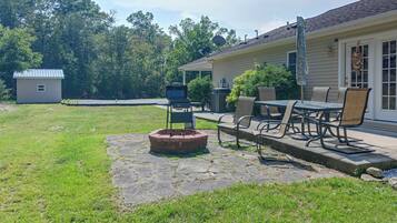 A backyard with a fire pit, outdoor furniture, and a house with a satellite dish.